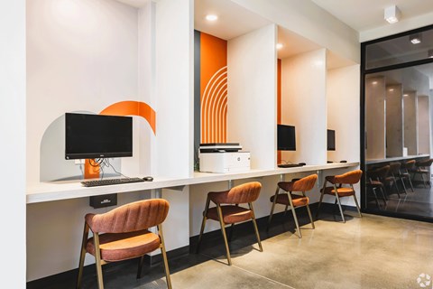 A modern office with orange accents and a computer on the desk.