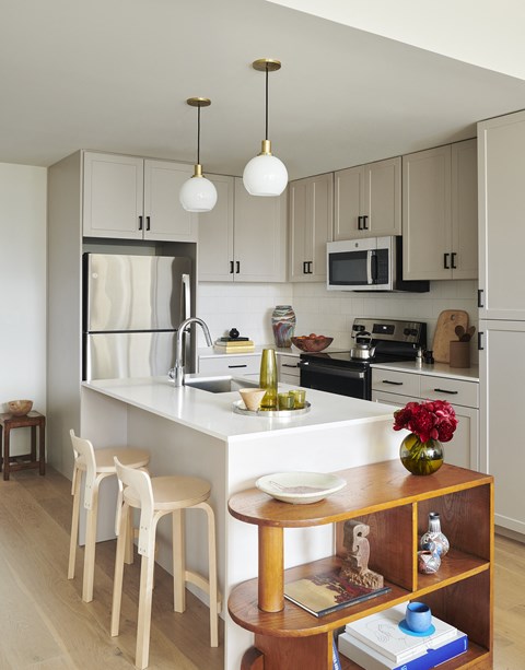 A kitchen with a white counter and wooden chairs.