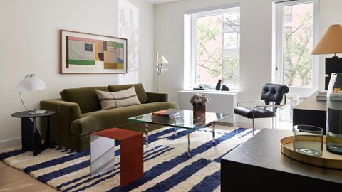 A living room with a green couch, a coffee table, and a painting on the wall.