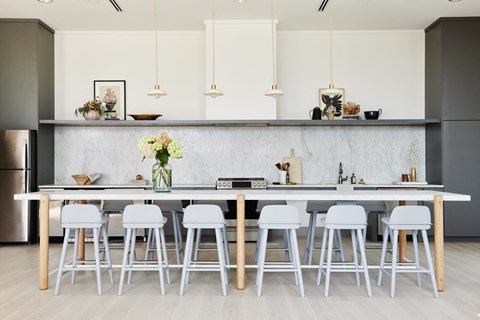 a kitchen with white stools and a long island with a sink and a counter