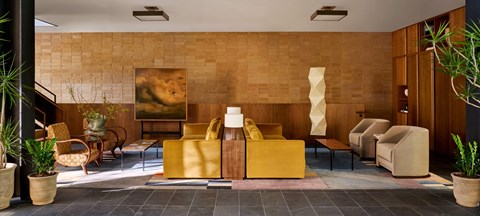 A living room with a yellow sofa and a painting on the wall.