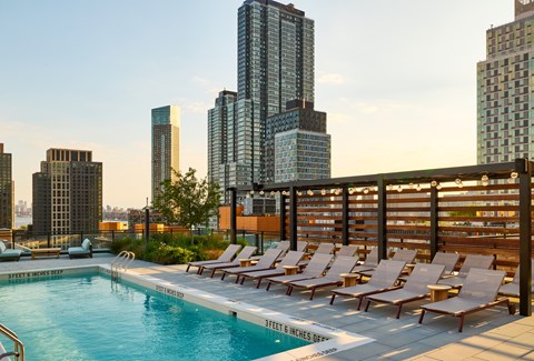 A pool with chairs and a sign that says "SPECTACULAR VIEWS" in front of a city skyline.