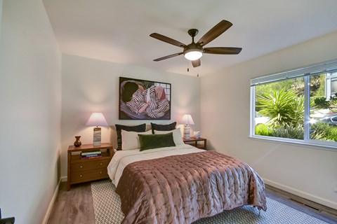 A bedroom with a bed, nightstands, and a ceiling fan.
