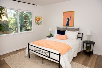 a bedroom with white walls and a bed with an orange and black blanket