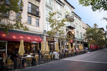 A street view of a restaurant with tables and chairs outside.
