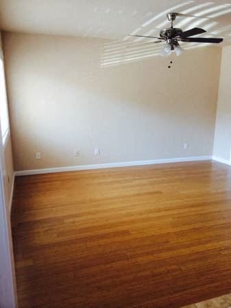 A room with a ceiling fan and wooden flooring.