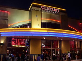 A cinema named Century Theatres is brightly lit up at night.