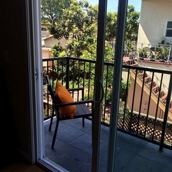 A balcony with a chair and a table with a pillow on it.