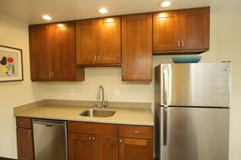 A kitchen with a refrigerator, sink, and cabinets.
