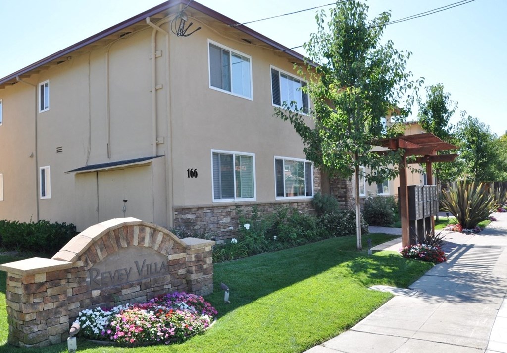 a side view of a house with a sidewalk in front of it
