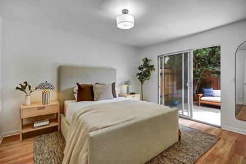 A bedroom with a large bed and a sliding glass door.