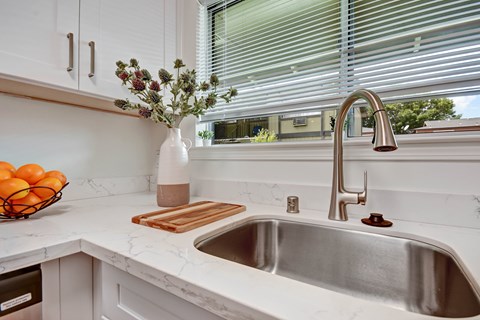 A kitchen with a white sink and a vase of flowers.