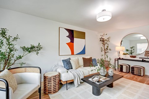 A living room with a white couch, a coffee table, and a large abstract painting on the wall.