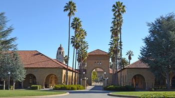A building with a red roof and palm trees in front.