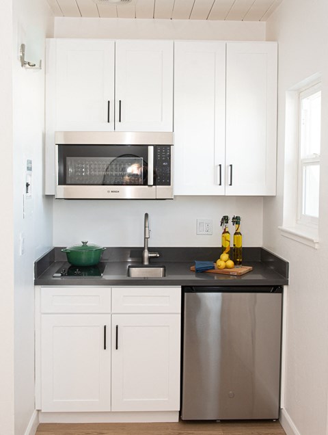 a small kitchen with white cabinets and a sink and a microwave