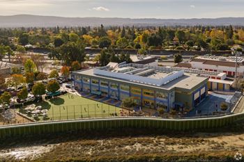 an aerial view of a building with a tennis court in front of it