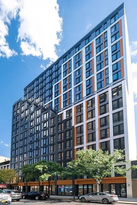 A modern multi-story building with a parking lot in front.