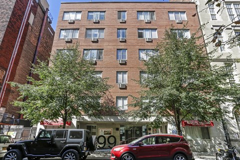 A black Jeep is parked in front of a building with the number 99 on it.