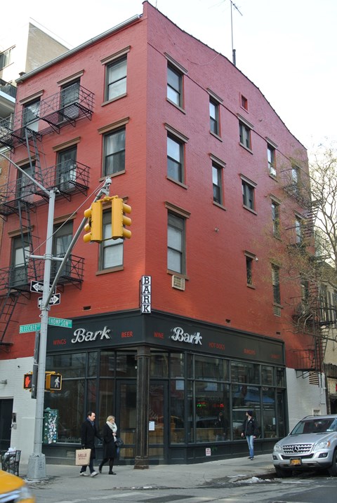 A red building with a black awning and a couple walking in front of it.