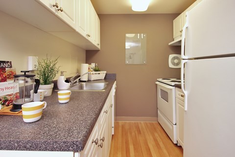 A kitchen with a granite countertop and white appliances.