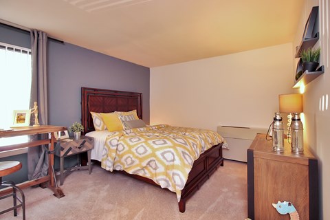 A bedroom with a bed, nightstand, and window.