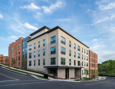 A modern multi-story building with a parking lot in front.