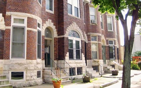 A red brick building with a black iron railing on the steps.
