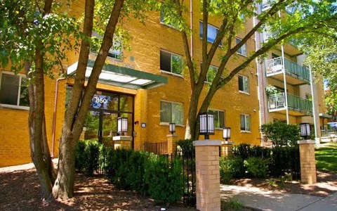 A yellow building with a green awning and a tree in front.