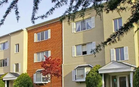 A row of apartment buildings with trees in front.