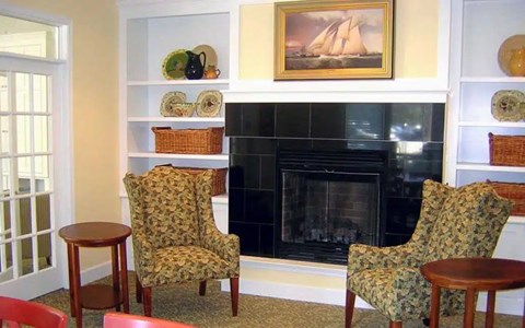 A living room with a fireplace and two chairs.