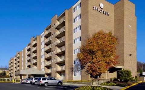 Spectrum apartment building with cars parked in front.