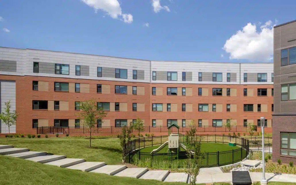 A large red brick building with a playground in front.