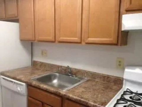 A kitchen with brown cabinets and a white dishwasher.
