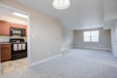 A spacious living room with a carpeted floor and a window.