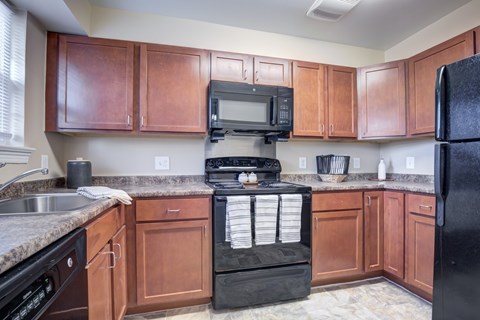 A kitchen with brown cabinets and a black refrigerator.
