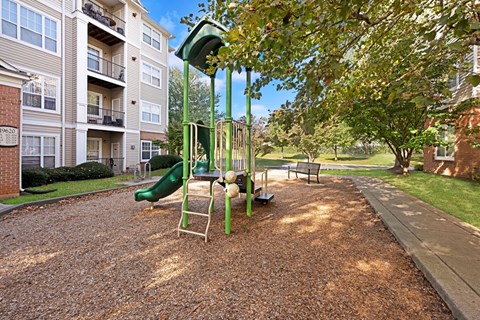 A playground with a green slide and a yellow swing set.