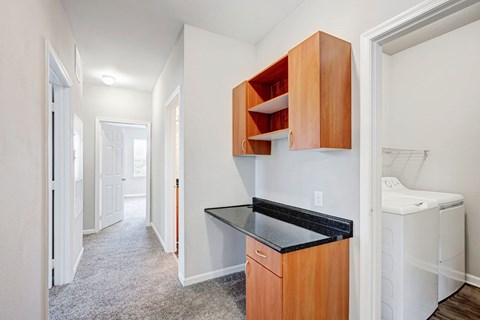 A small kitchen with a black counter top and wooden cabinets.
