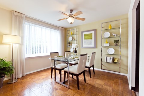 A dining room with a table set for two and a ceiling fan.