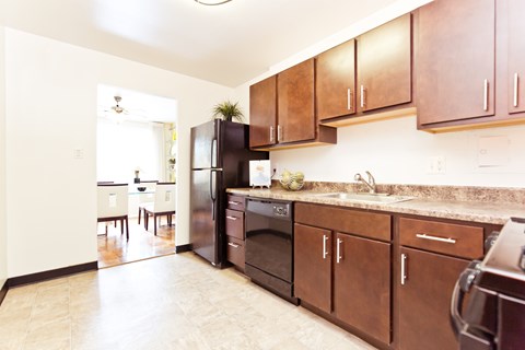 A kitchen with brown cabinets and a black refrigerator.