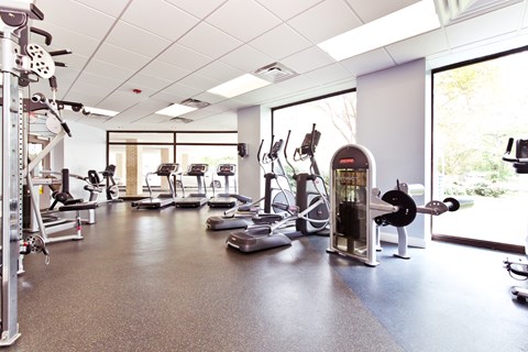 A gym with a variety of equipment including treadmills, weights, and exercise machines.