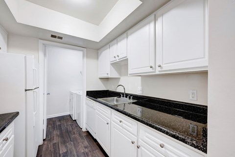 A kitchen with white cabinets and a black counter top.