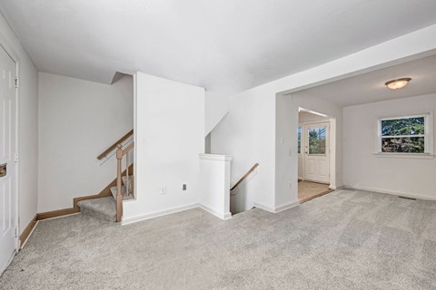 A spacious room with a staircase leading to the upper level.