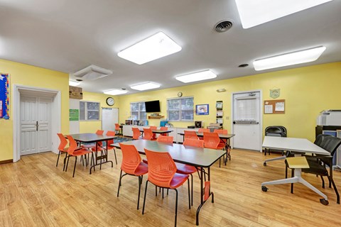 A room with tables and chairs and a white ceiling.