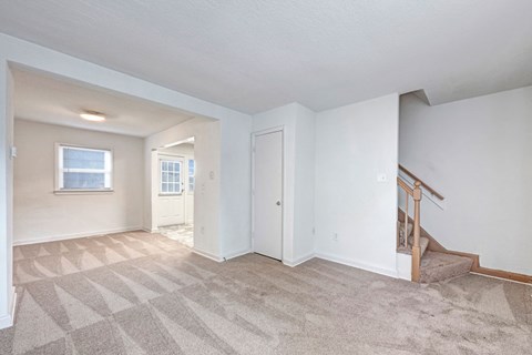 A room with a carpeted floor and a staircase.