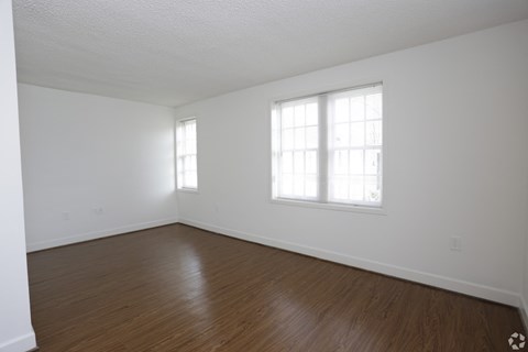 the living room of an empty house with white walls and wood floors