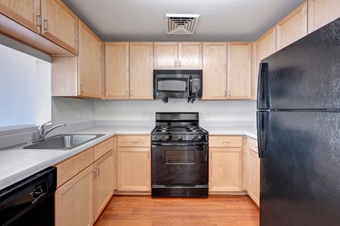 A black refrigerator sits in a kitchen with wooden cabinets.