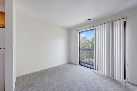 A room with a sliding glass door leading to a balcony.