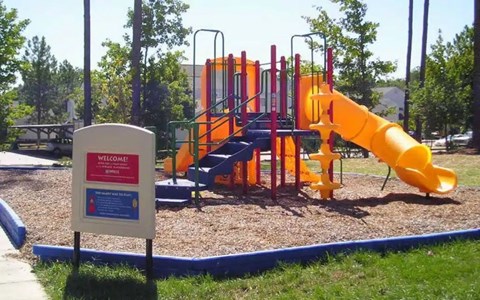 A playground with a yellow slide and a sign that says "Welcome".