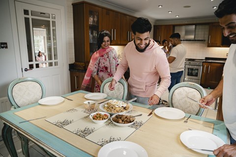 A group of people are gathered around a table with plates of food.