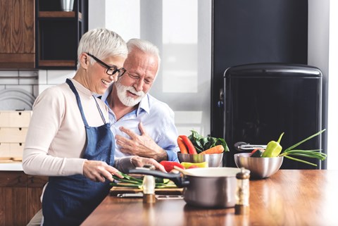 An older couple is preparing food together in the kitchen.
